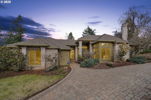 prairie-style home featuring brick siding and a chimney