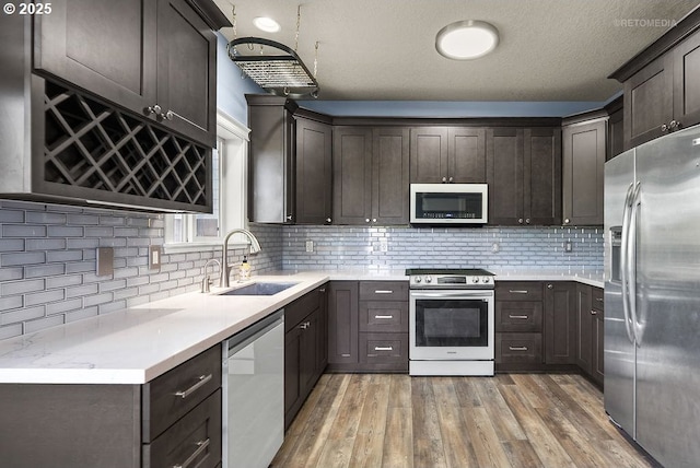 2820 23rd Pl, Forest Grove, OR 97116 - kitchen featuring appliances with stainless steel finishes, a sink, dark brown cabinetry, light wood finished floors, and decorative backsplash