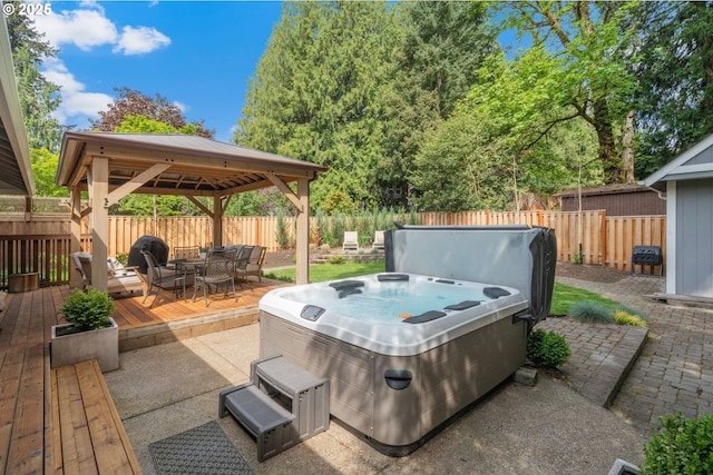view of patio / terrace featuring a gazebo, a hot tub, outdoor dining area, a deck, and a fenced backyard