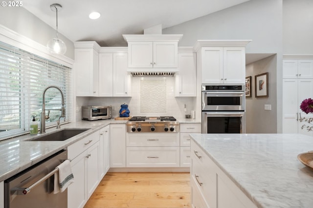 kitchen with a sink, stainless steel appliances, lofted ceiling, decorative backsplash, and light wood-style flooring