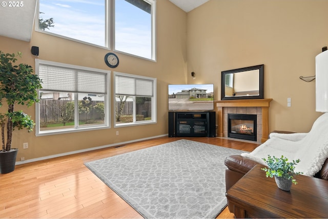 living area featuring visible vents, plenty of natural light, wood finished floors, and a tiled fireplace