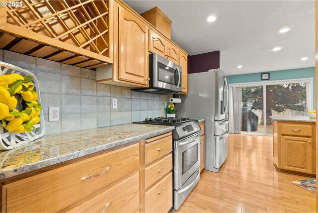 kitchen featuring light stone countertops, decorative backsplash, recessed lighting, appliances with stainless steel finishes, and light wood-style floors