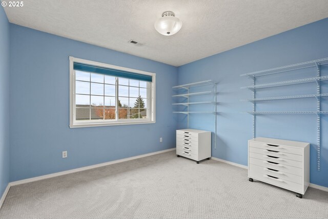 unfurnished bedroom featuring baseboards, visible vents, carpet floors, and a textured ceiling