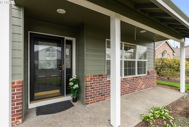 entrance to property with covered porch and brick siding