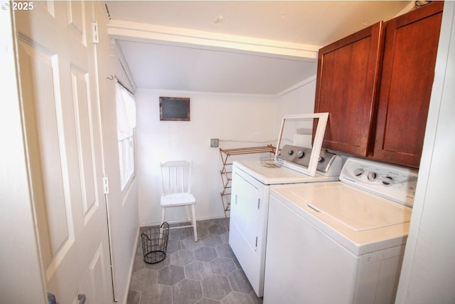 laundry area featuring dark tile patterned flooring, washer and clothes dryer, and cabinets