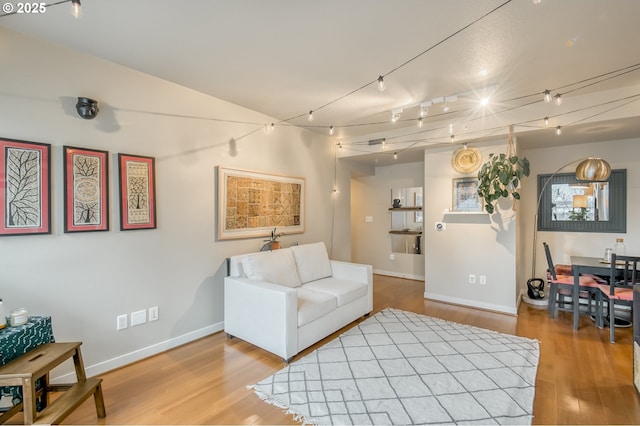 living room featuring baseboards, wood finished floors, and track lighting