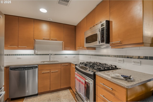 kitchen with a sink, stainless steel appliances, visible vents, and decorative backsplash