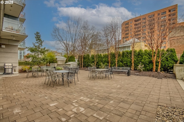 view of patio featuring outdoor dining area, an outbuilding, grilling area, and a shed