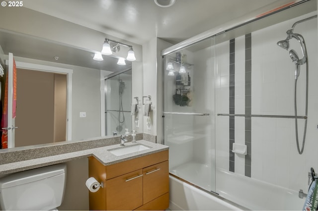 full bath featuring vanity, toilet, and combined bath / shower with glass door