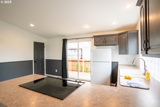 906 N Railroad Ave, Ridgefield, WA 98642 - kitchen featuring freestanding refrigerator, black electric stovetop, vaulted ceiling, light countertops, and a wainscoted wall
