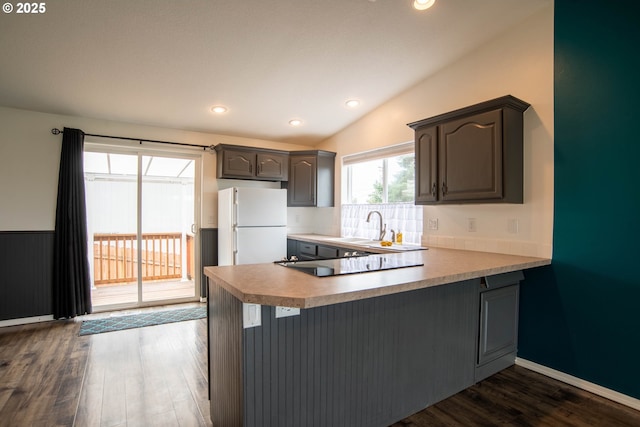 906 N Railroad Ave, Ridgefield, WA 98642 - kitchen featuring freestanding refrigerator, a peninsula, black electric cooktop, dark wood-style flooring, and vaulted ceiling