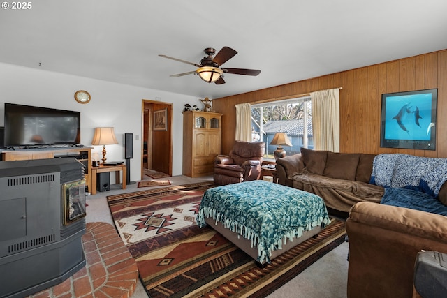 878 NW Warrenton Dr, Warrenton, OR 97146 - carpeted living room featuring a wood stove, wooden walls, and a ceiling fan