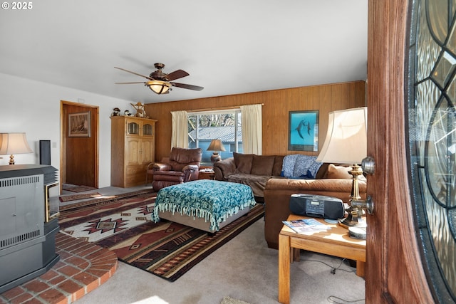 878 NW Warrenton Dr, Warrenton, OR 97146 - living room featuring carpet floors, wooden walls, ceiling fan, and a wood stove