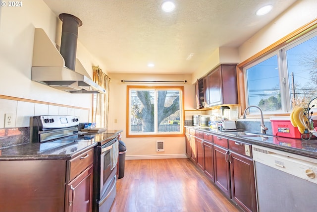 kitchen featuring sink, dishwashing machine, stainless steel range with electric stovetop, exhaust hood, and light hardwood / wood-style flooring