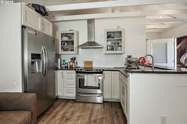 kitchen featuring dark countertops, appliances with stainless steel finishes, wall chimney exhaust hood, and dark wood finished floors