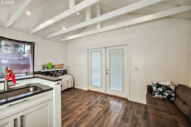 kitchen with dark countertops, french doors, vaulted ceiling with beams, and a sink