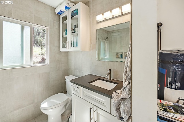 bathroom with vanity, tile walls, toilet, and a shower