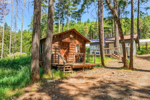 exterior space with a wooden deck, a forest view, and an outdoor structure