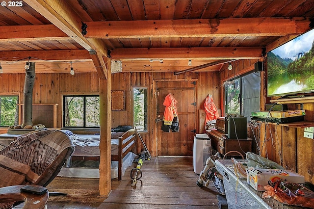 bedroom with beam ceiling, wood walls, multiple windows, and wood-type flooring