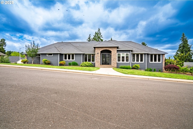 single story home featuring roof with shingles and a front lawn