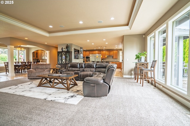 living area featuring a raised ceiling, arched walkways, crown molding, light carpet, and recessed lighting