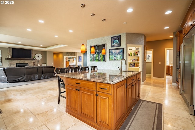 kitchen featuring a sink, brown cabinets, a breakfast bar, recessed lighting, and open floor plan