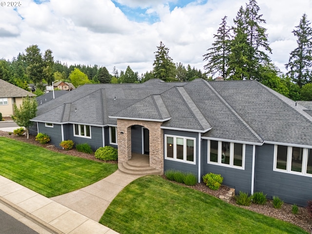 ranch-style home with a front yard and roof with shingles