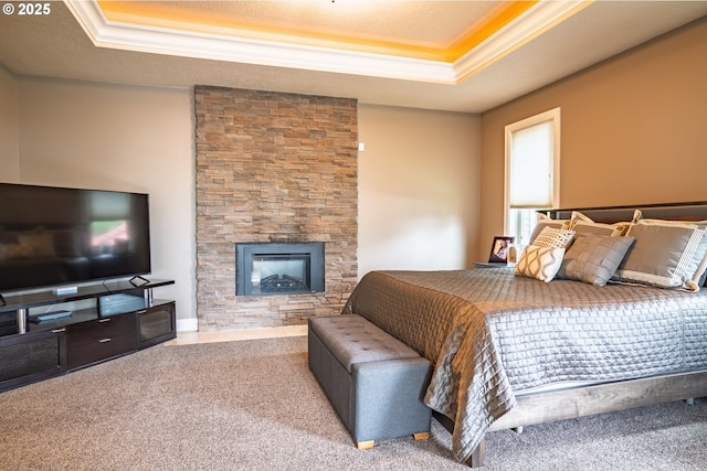 bedroom with a raised ceiling, crown molding, a fireplace, and carpet