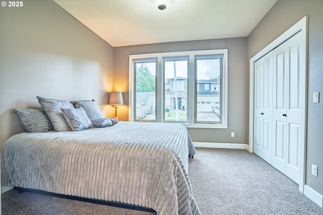 carpeted bedroom featuring baseboards, a closet, and lofted ceiling