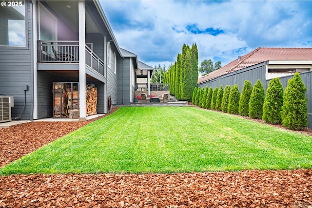view of green lawn with a balcony and central air condition unit