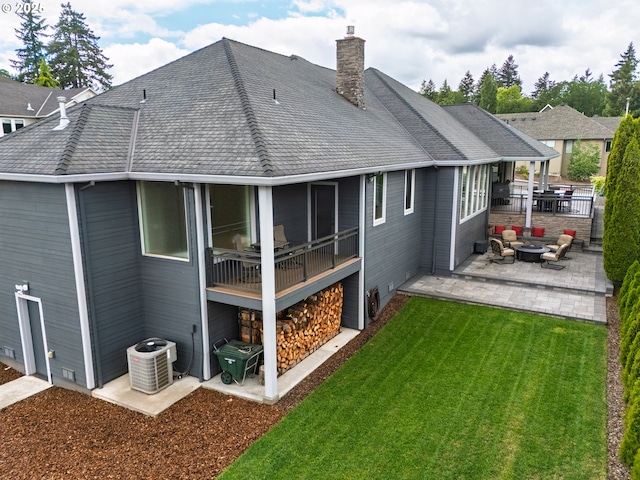 rear view of property with a patio, central AC, a yard, a chimney, and an outdoor fire pit