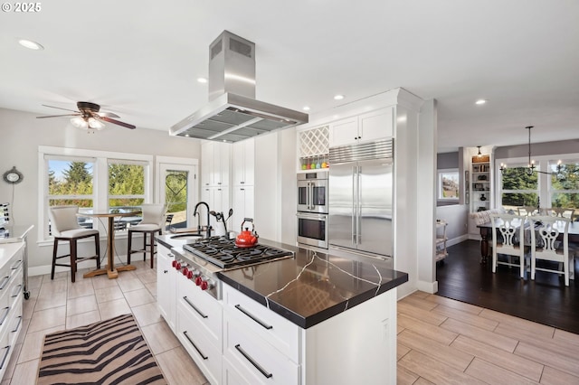 20265 SE Poco Ln, Amity, OR 97101 - kitchen with island exhaust hood, appliances with stainless steel finishes, a sink, ceiling fan, and baseboards