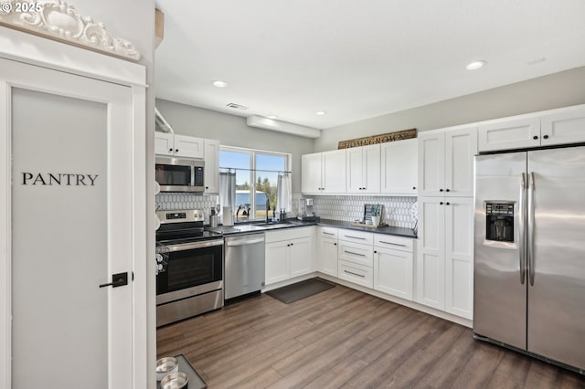 20265 SE Poco Ln, Amity, OR 97101 - kitchen with appliances with stainless steel finishes, dark countertops, tasteful backsplash, dark wood-style flooring, and recessed lighting