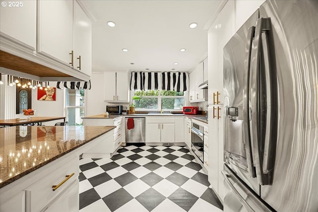 kitchen featuring white cabinetry, stainless steel appliances, and dark stone countertops