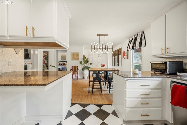 kitchen with backsplash, dark stone counters, hanging light fixtures, and white cabinets