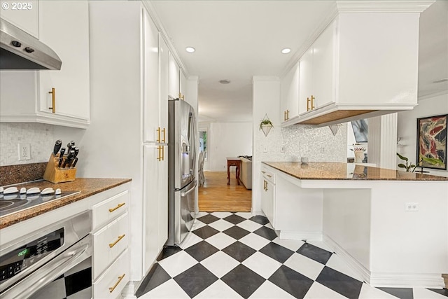 kitchen featuring stainless steel appliances, ornamental molding, white cabinets, decorative backsplash, and dark stone counters