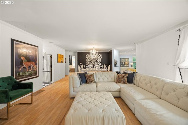 living room featuring crown molding, a notable chandelier, and light wood-type flooring