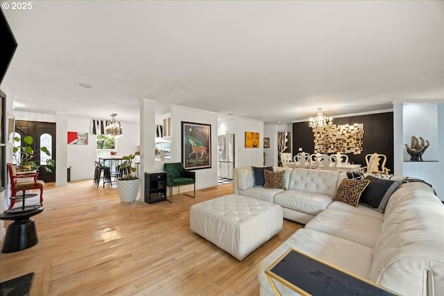 living room featuring an inviting chandelier, ornamental molding, and light wood-type flooring