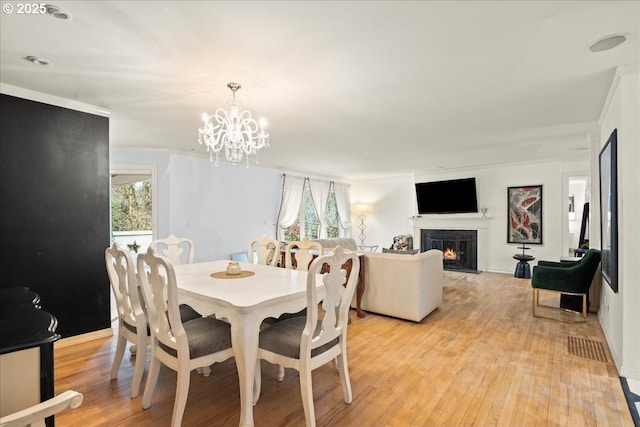 dining area featuring a healthy amount of sunlight, a notable chandelier, and light hardwood / wood-style floors