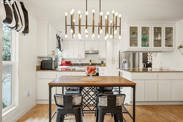 kitchen with sink, decorative light fixtures, light hardwood / wood-style floors, and white cabinets