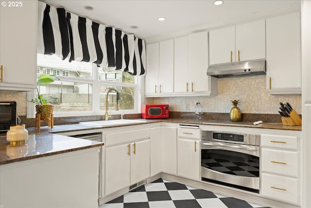 kitchen with white cabinetry, stainless steel oven, sink, and backsplash