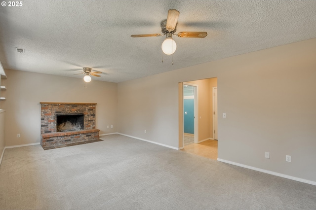 unfurnished living room featuring ceiling fan, light colored carpet, a brick fireplace, and a textured ceiling