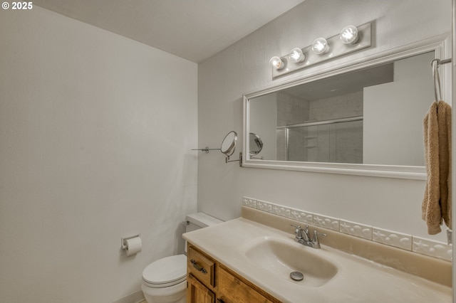 bathroom featuring vanity, a shower with shower door, and toilet