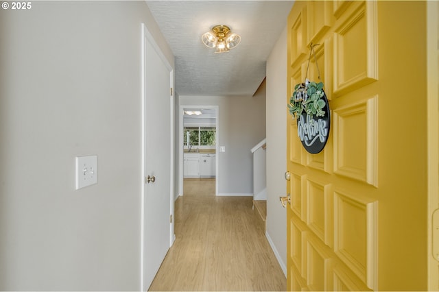 corridor featuring sink, a textured ceiling, and light hardwood / wood-style flooring