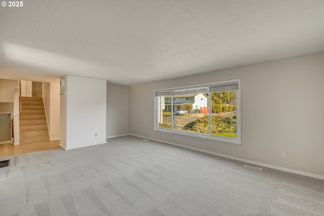 spare room featuring light carpet and a textured ceiling