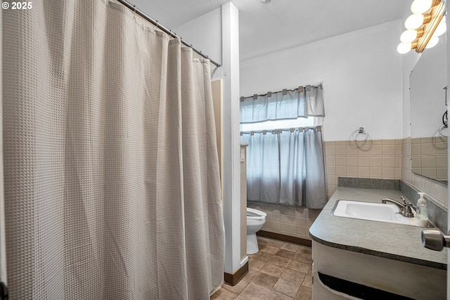 bathroom with tile walls, a shower with shower curtain, vanity, tile patterned floors, and toilet