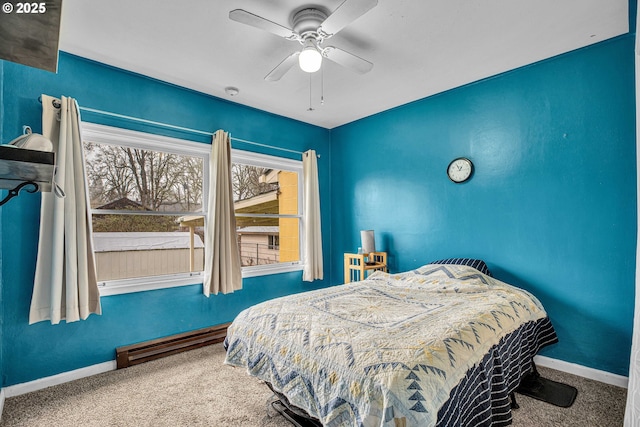 carpeted bedroom with ceiling fan and a baseboard heating unit