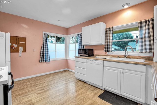 kitchen featuring white appliances, sink, light hardwood / wood-style flooring, and white cabinets