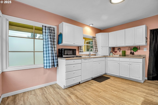 kitchen featuring white dishwasher, sink, and white cabinets