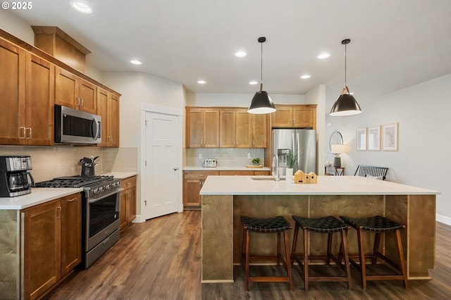 3466 N Holladay St, Cornelius, OR 97124 - kitchen featuring stainless steel appliances, dark wood-style floors, a breakfast bar, backsplash, and a kitchen island with sink